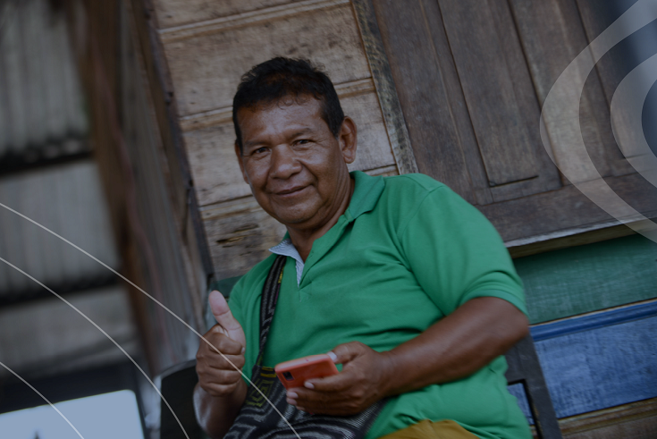 Un señor de camisa verde con su dispositivo movíl